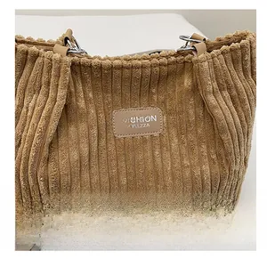 Close-up of khaki corduroy tote bag with chain link and faux leather logo patch