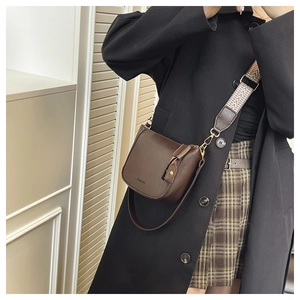 Detail of dark brown saddle bag with vintage matte texture and geometric wide strap
