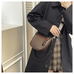 Detail of dark brown leather crossbody bag with wide geometric pattern strap and FASHION logo