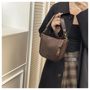 Detail of dark brown semi-moon saddle bag with golden zipper and wide shoulder strap