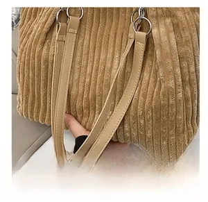 Detail of soft corduroy tote bag strap with sturdy metal ring and leather brand tag