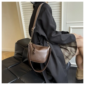 Detail of dark brown leather bucket bag featuring wide jacquard strap and fashion lettering