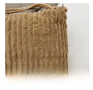 Gros plan sur la texture en velours côtelé marron et la bandoulière de ce sac chic