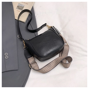 Detail view of black vintage bucket bag featuring a wide woven strap and gold hardware