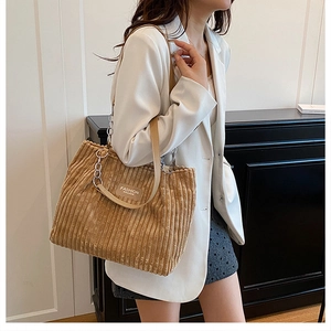 Brown corduroy tote bag showing large capacity and chain shoulder strap on a model