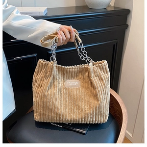Close-up of khaki corduroy tote bag with silver chain handle and fashion leather patch