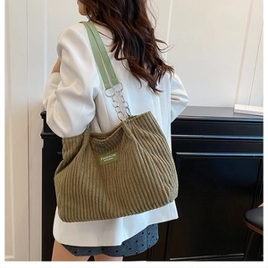 Detail of olive green corduroy shoulder bag showing fabric texture and metal chain strap