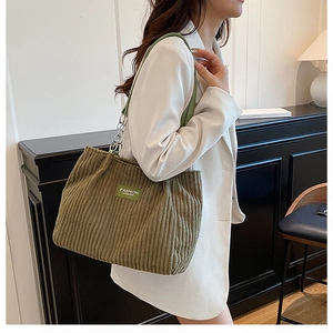 Detailed close-up of olive green corduroy texture with chain strap and fashion label on the bag