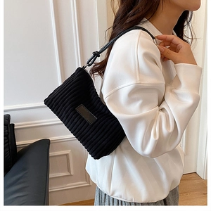Gros plan d'un sac à bandoulière en velours côtelé noir avec patch en cuir sur modèle