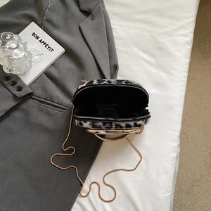 Leopard print crossbody bag with gold chain and metal ring handle on grey blazer