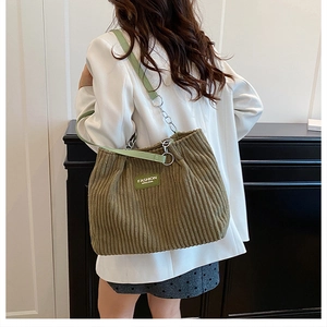 Olive green corduroy tote bag with chain strap shown on model shoulder for daily commute