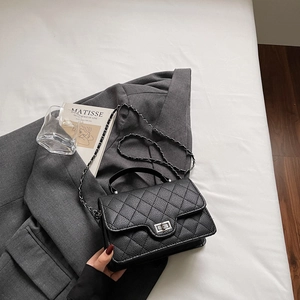 Détail du sac à main en cuir matelassé noir avec fermoir rotatif argenté sur un veston
