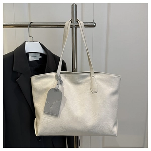 Close-up of white leather tote bag with pleated texture and stylish tag detail