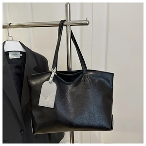 Detail of soft black leather tote bag texture with minimalist decorative gray tag