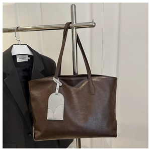 Detail of soft brown faux leather texture and elegant hanging strap on large tote bag
