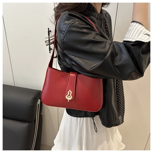Detail of red matte leather shoulder bag with decorative gold hollow buckle on model