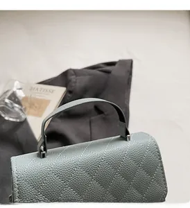 Close-up of diamond quilted texture and sturdy top handle on light blue crossbody bag