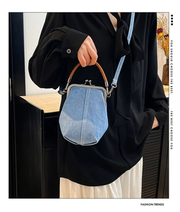 Detail of light blue denim shell bag with white stitching and silver kiss-lock closure