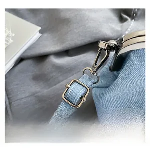 Close-up of adjustable metal buckle and hook on blue denim bucket bag shoulder strap