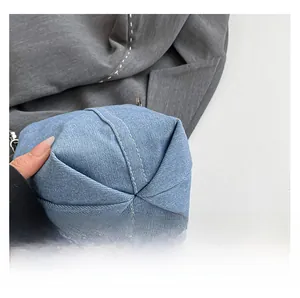 Detailed close-up of the cross-fold bottom design and white stitching on denim bucket bag