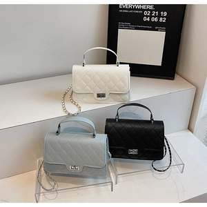 Detail of quilted leather mini bags with metal chain straps in white, blue and black