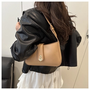 Détail de la boucle métallique dorée en forme de gourde sur un sac à bandoulière