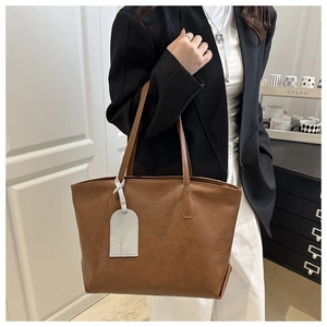 Detail of soft leather texture and long shoulder straps on the large brown tote bag