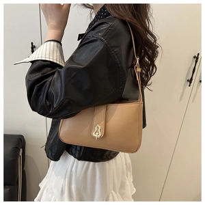 Detail of khaki leather shoulder bag featuring unique gold wave-shaped metal buckle closure