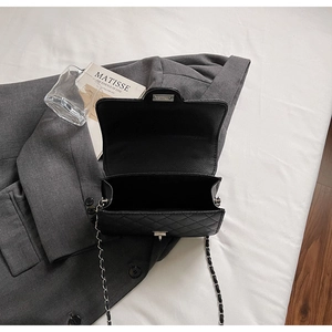 Détail du sac bandoulière matelassé noir ouvert montrant l'intérieur et le fermoir rotatif
