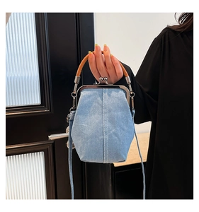Detailed view of vintage denim shell bag with blue fabric texture and metal frame