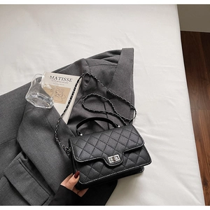 Détail du cuir matelassé noir et du fermoir rotatif en métal argenté de ce sac à main