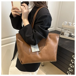 Detail view of a large brown leather tote bag with a gray accent pocket on a model