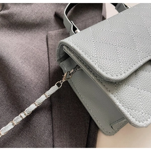 Détails de la texture du cuir bleu grainé et des surpiqûres en losanges sur le sac à main