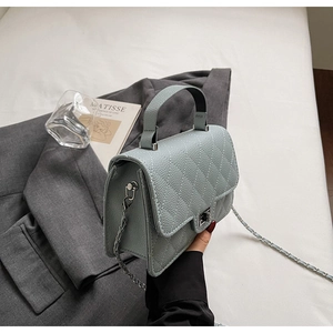 Détail du sac matelassé bleu-gris avec texture litchi et fermoir rotatif argenté