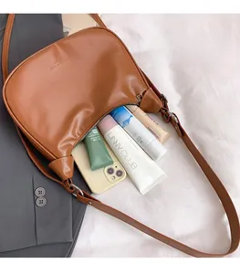 Top view of brown crescent bag interior showing space for cosmetics and a smartphone