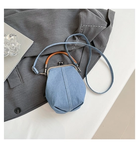 Macro detail of retro denim bucket bag featuring a metal frame clasp and brown leather handle