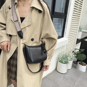Black matte leather bucket bag with ethnic woven wide shoulder strap in street style view