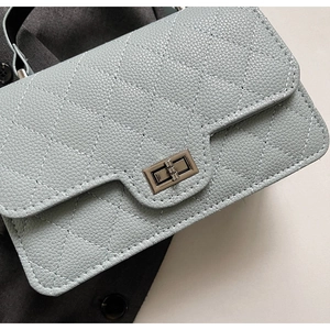 Détail d'un sac matelassé bleu clair avec fermoir rotatif argenté et cuir grainé lychee