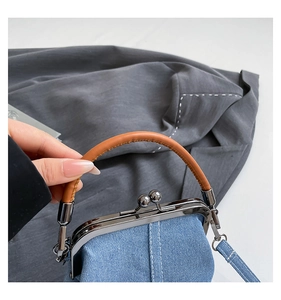 Detail of vintage denim bucket bag with metal clasp and brown leather handle strap