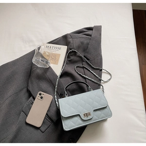 Vue à plat d'un sac à bandoulière matelassé bleu clair avec serrure argentée et chaîne