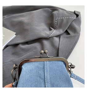 Close-up of light blue denim bucket bag featuring silver metal clasp and white stitching