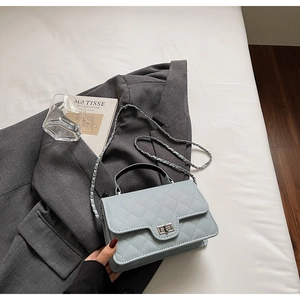 Détail du sac matelassé bleu clair avec fermoir argenté sur un costume gris
