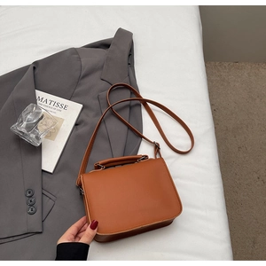 Elegant brown leather Cambridge bag styled with a grey blazer and lifestyle props