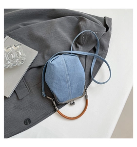 Detail of light blue denim bucket bag with brown leather handle and metal frame