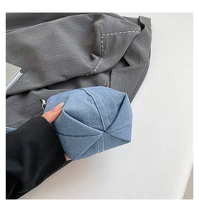 Detail view of denim bucket bag bottom showing white contrast stitching and D-ring