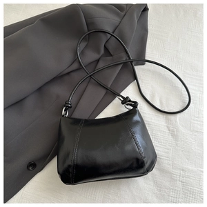Detail of black glossy PU leather handbag with vertical stitching and silver metal rings