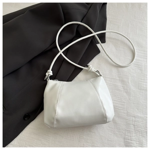 Detail of white leather dumpling bag with rounded silhouette and knot shoulder strap
