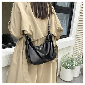 Detail of a black crescent shoulder bag with silver zipper and adjustable long strap