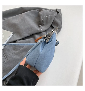 Detail of light blue denim bucket bag with retro metal clasp and brown round handle