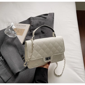 Détail du sac en cuir matelassé beige avec fermoir en métal, chaîne et poignée design